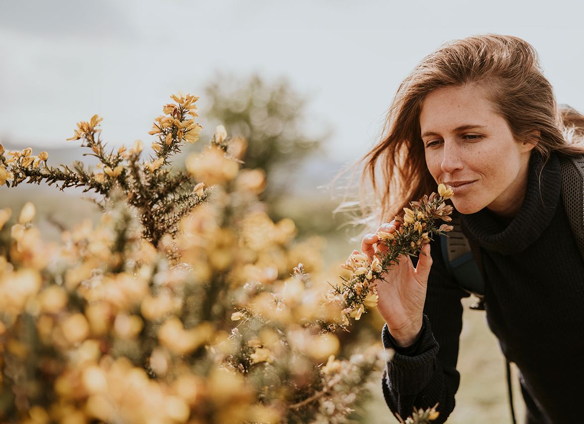 Woman smelling flowers in nature outdoors.
